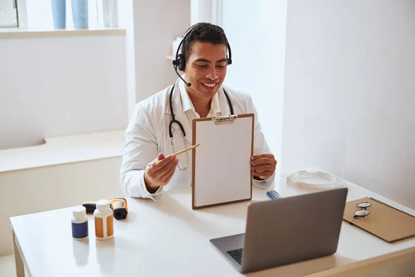 Médecin professionnel positif démontrant le livre blanc lors de l'appel vidéo pour un autre médecin — Photo