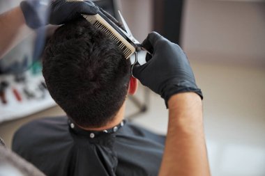 Tanımlanamayan berber odada tarak ve makasla saç kesiyor.