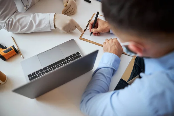 Läkare i handskar på bordet nära laptopen och ett annat verktyg för att mäta hälsa — Stockfoto