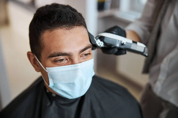 Fokuserad bild av kunden i skönhetssalong med frisör gör frisyr med elektrisk hårmaskin — Stockfoto