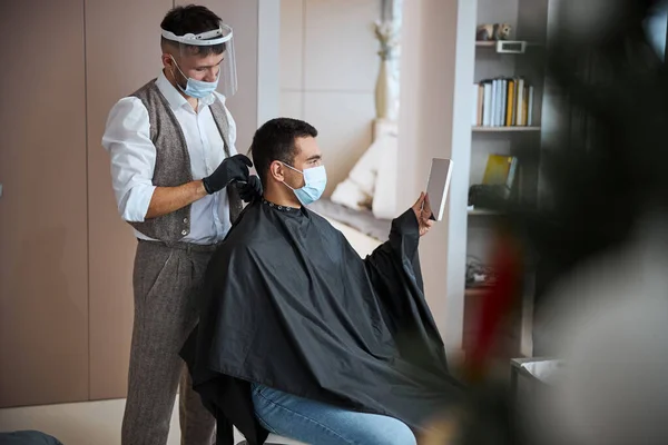 Homem não reconhecido com cabelo escuro visitando barbearia enquanto recebendo novo estilo de cabelo — Fotografia de Stock