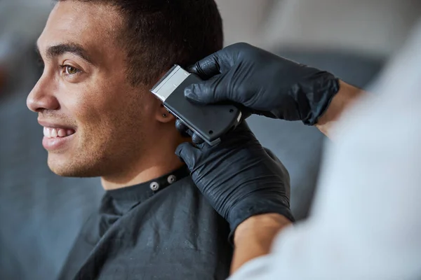 Barbeiro mão em luvas de medicina fazendo novo estilo para o cliente no salão de beleza — Fotografia de Stock