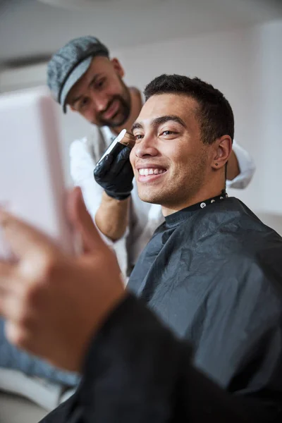 Bonito homem olhando para frente, enquanto barbeiro usando máquina elétrica moderna para o estilo de cabelo — Fotografia de Stock