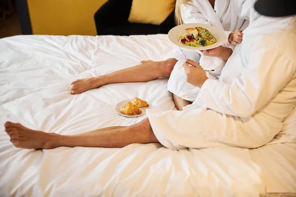 Couple pieds nus en peignoirs éponge prenant le petit déjeuner dans une chambre d'hôtel — Photo