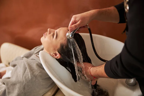 Спокойная кавказская женщина проходит процедуру мойки волос — стоковое фото