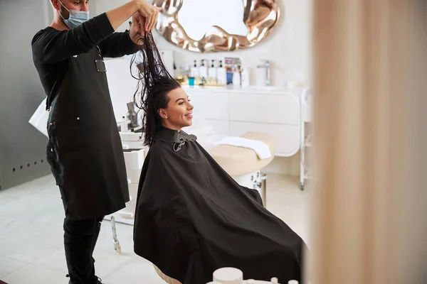 Удовлетворенный клиент, сидящий в кресле парикмахера во время прически — стоковое фото