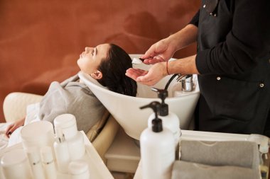 Saç köpüğünü kadın saçına süren stilist.