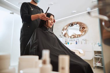 Taraklı stilist müşterisinin başını öne eğiyor