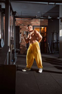 Spor salonunda tişörtsüz egzersiz yapan yakışıklı bir adam.