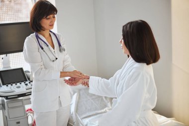 Deneyimli kardiyolog hastanın kalp atışlarını kontrol ediyor.