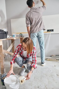 Smiling lady helping her husband to renovate the flat