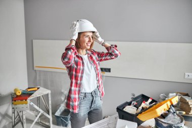 İş yerinde kasket takan neşeli bir işçi kadın.