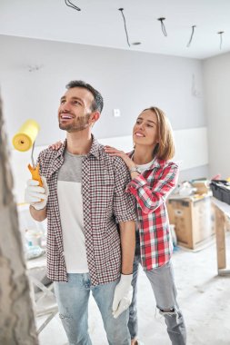 Memnun genç ressam boyalı duvara hayran.