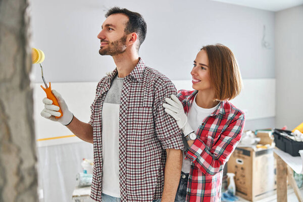 Pleased young wife admiring her husband work
