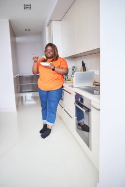 Büyük beden kadın salatasını evde yiyor.