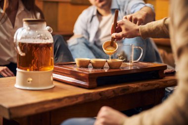 Erkek eli, rahat bir kafede fincanlara çay dolduruyor.