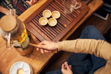 Genç adam kafeteryada çay seremonisi sırasında sıcak içecek hazırlıyor.