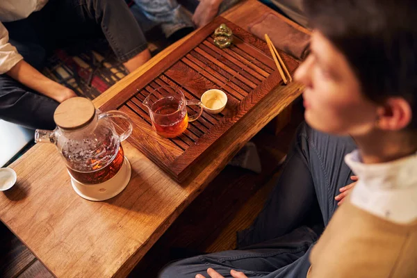 Genç insanlar çay takımıyla masada oturuyorlar.