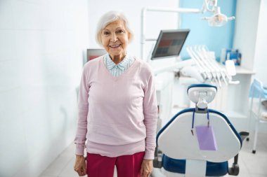 Dişçi koltuğunun yanında duran emekli kadın.