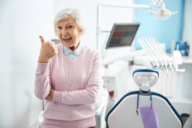 Yaşlı kadın dişçi malzemelerinin kalitesini onaylıyor.