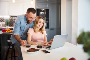 Mutlu genç çift evlerinde modern laptop kullanıyor.