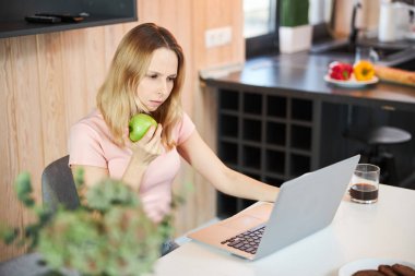 Evinde modern laptop kullanan elmalı çekici bir kadın.