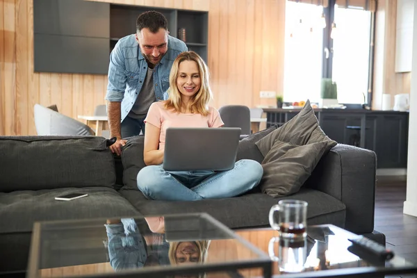 Evde dizüstü bilgisayar kullanan neşeli karı koca.