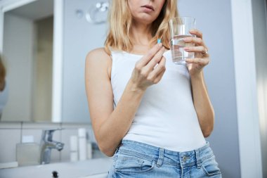 Evdeki banyoda hap alan genç bir kadın.