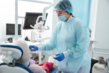 Kadın diş cerrahı hastaya diş kontrolü yapıyor.