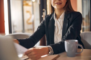 Ofisinde çalışan gülümseyen siyah saçlı kadın tasarımcı.