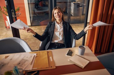 Kameraya poz veren, teknik çizimleri olan kadın mimar.