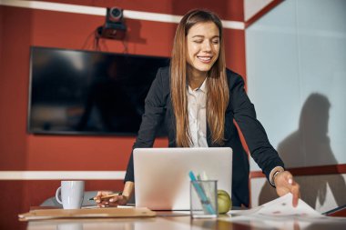 Hevesli bayan mühendis masadaki teknik çizimlere bakıyor.