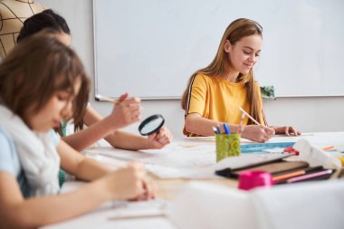 Dikiş atölyesinde kıyafet çizen sevimli çocuklar.