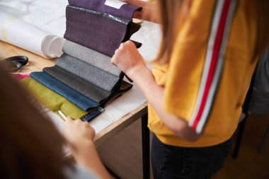 Dikiş atölyesinde kumaş örnekleri seçen kadın çocuklar