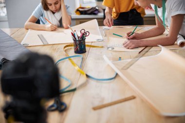 Sevimli bayan çocuklar atölyede dikiş desenleri çiziyorlar.