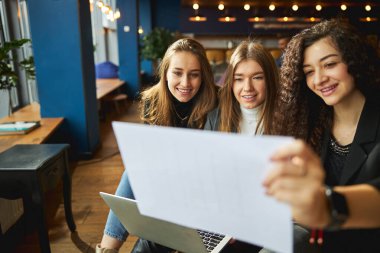 Neşeli iş arkadaşları iş yerinde proje taslağı çalışıyor.