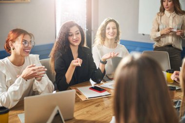 Ofiste iş projesini tartışan neşeli genç kadınlar.