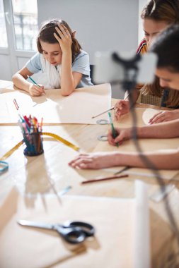 Sevimli bayan çocuklar atölyede dikiş desenleri çiziyorlar.