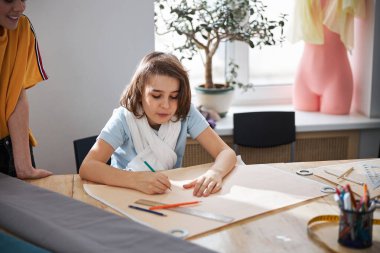 Küçük sevimli terzi atölyede dikiş deseni yapıyor.