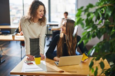 Laptop kullanan ve iş arkadaşlarıyla konuşan çekici bir kadın.