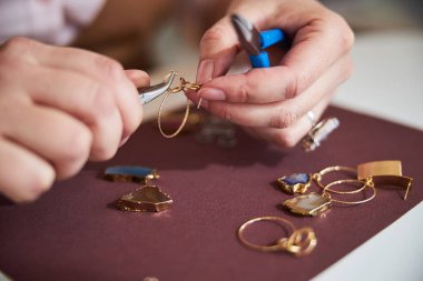 Yetenekli beyaz kadın kuyumcu bir küpe yapıyor.