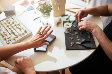 Zanaatkar kadın yeni el yapımı mücevherini inceliyor.