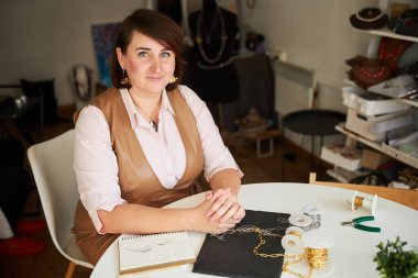 İş yerinde kameraya poz veren sakin bir mücevher tasarımcısı.