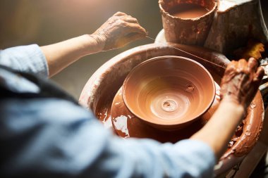 Çömlek atölyesinde kilden kase yapan yaşlı kadın elleri.