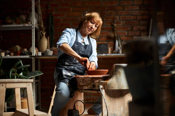 Charming old woman making clay bowl in pottery workshop — Stock Photo, Image