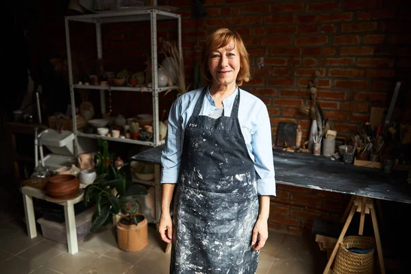 Encantadora mujer mayor de pie en el taller de cerámica —  Fotos de Stock