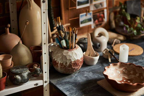 Table with pottery and paint brushes in workshop