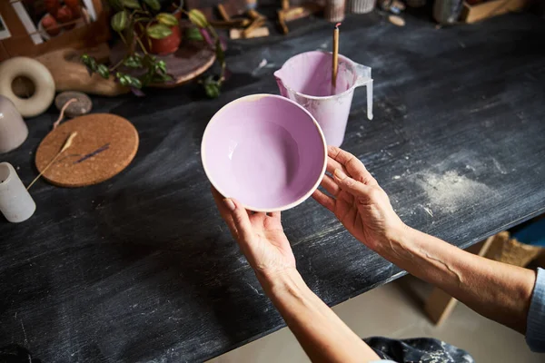 Alfarero femenino sosteniendo cuenco pintado en taller de cerámica — Foto de Stock