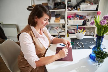 Goldsmith penseyi kullanarak bir kolyeyi büküyor.