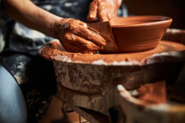 Yaşlı kadın elleri atölyede çömlek yapıyor.